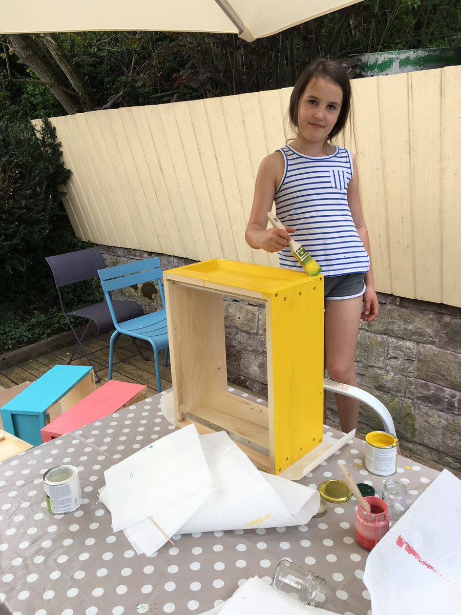 Sophie streicht einen Bienenkasten gelb